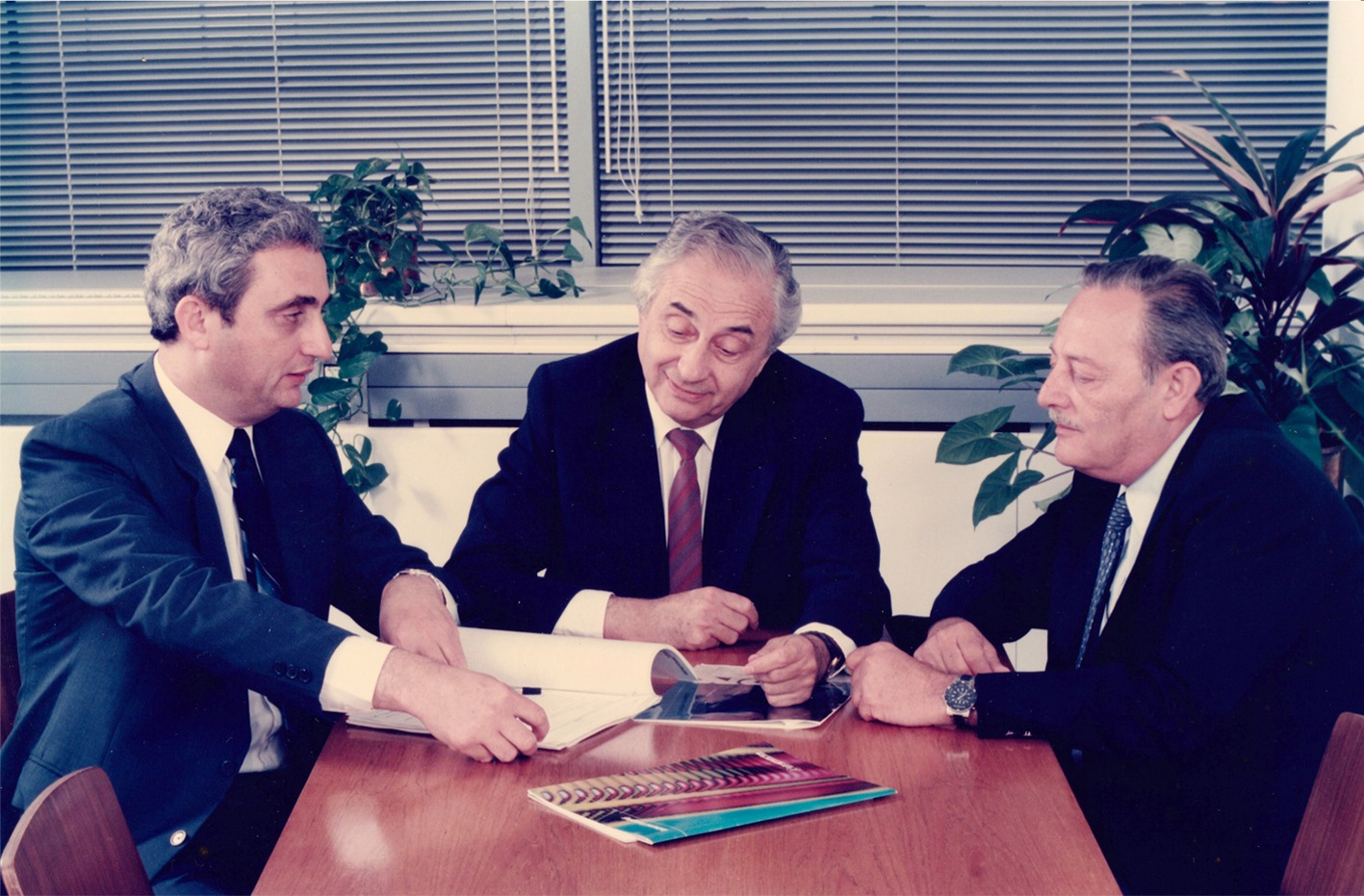 Emmanuel Gill seated at a desk with Uzia Galil and Beny Peled